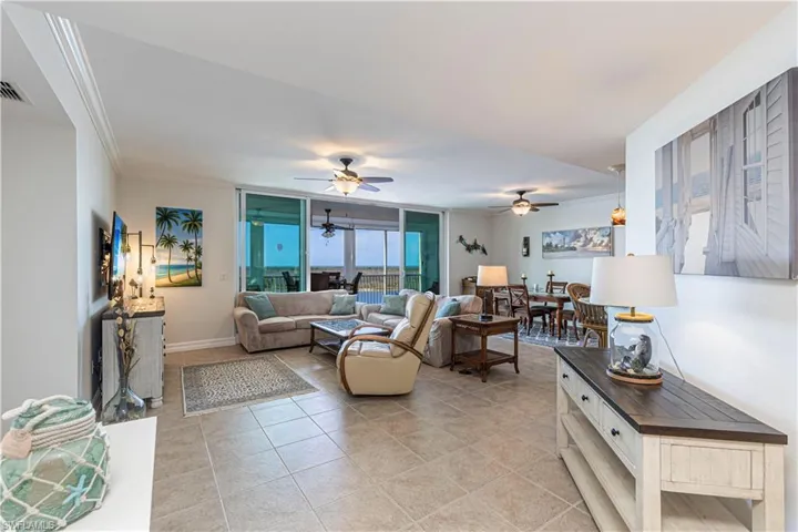 Living room featuring light tile patterned floors, a ceiling fan, and crown molding