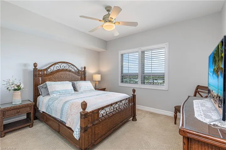 Bedroom with light colored carpet, baseboards, and ceiling fan