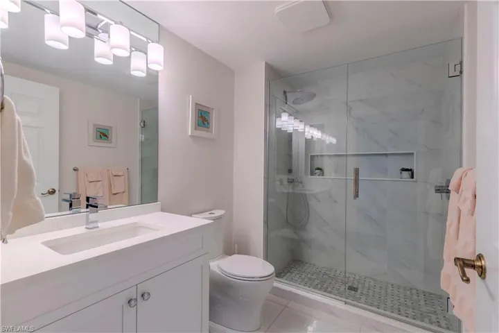 Bathroom featuring a marble finish shower, toilet, vanity, and tile patterned flooring