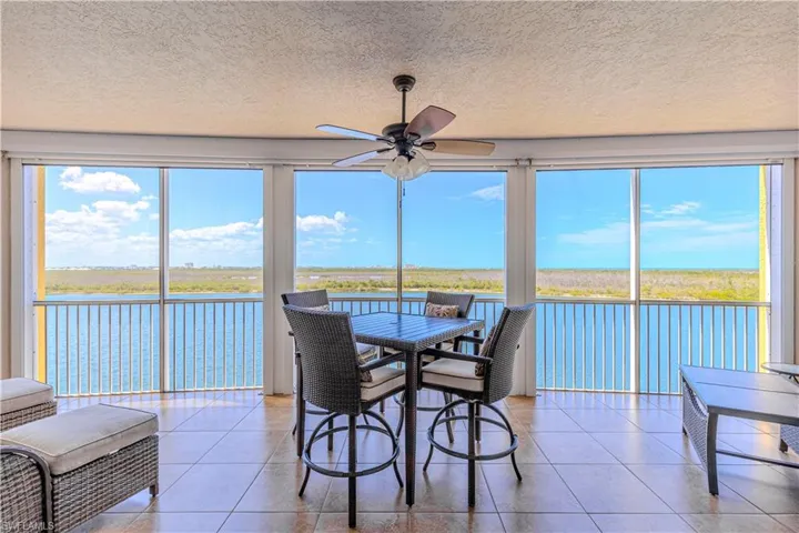 Sunroom featuring tile patterned flooring, a textured ceiling, and a water view