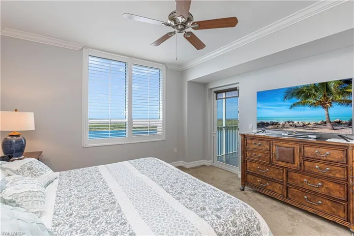 Bedroom with access to outside, light colored carpet, multiple windows, crown molding, and baseboards