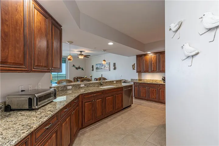 Kitchen with a sink, dishwasher, hanging light fixtures, ceiling fan, and light tile patterned flooring