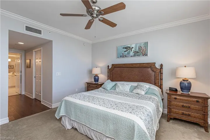 Bedroom featuring carpet flooring, ornamental molding, baseboards, a ceiling fan, and ensuite bath