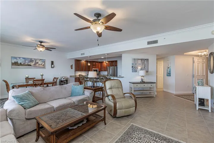 Living area with ceiling fan, crown molding, baseboards, and light tile patterned floors