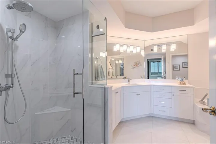Full bathroom featuring a marble finish shower, tile patterned floors, and vanity