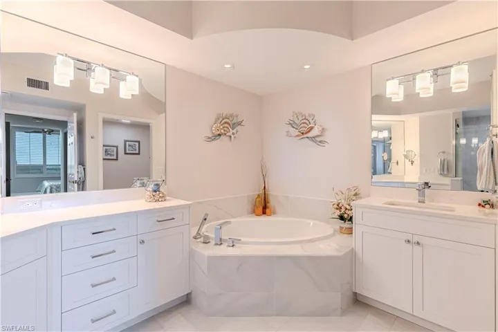 Ensuite bathroom with a bath, two vanities, tile patterned floors, and recessed lighting