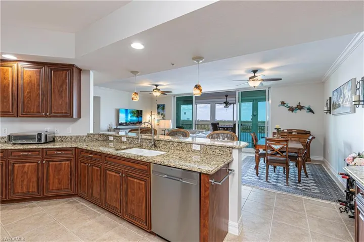 Kitchen with dishwasher, a sink, a peninsula, light tile patterned floors, and crown molding
