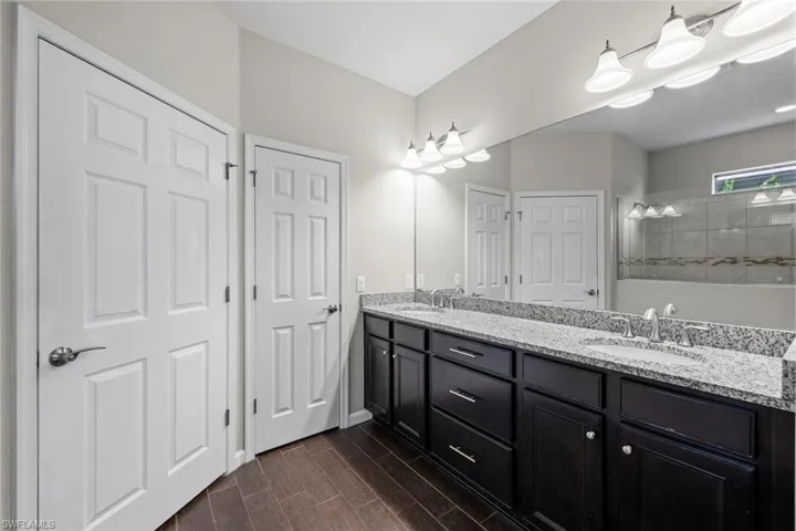 Bathroom featuring wood tiled floor, double vanity, a sink, and walk in shower
