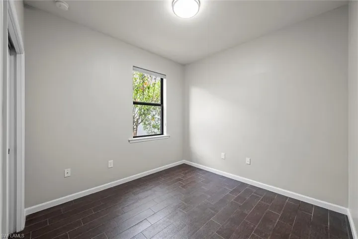 Unfurnished room with dark wood-style floors, baseboards, ceiling fan, and visible vents