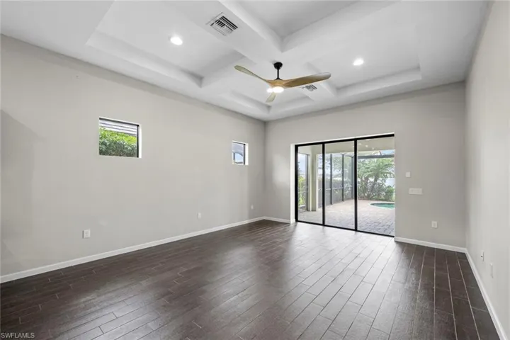 Empty room featuring dark wood finished floors, visible vents, and plenty of natural light