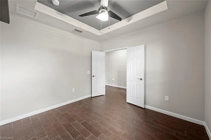 Unfurnished room with a raised ceiling, baseboards, ceiling fan, and visible vents