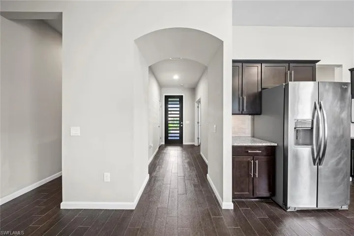 Hall featuring arched walkways, dark wood-style floors, baseboards, and visible vents