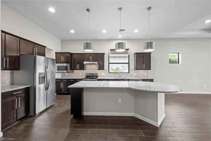 Kitchen with tasteful backsplash, under cabinet range hood, a kitchen island, dark brown cabinetry, and appliances with stainless steel finishes