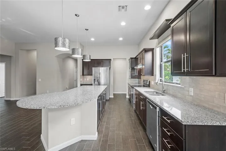 Kitchen featuring a spacious island, a sink, visible vents, dark brown cabinetry, and appliances with stainless steel finishes