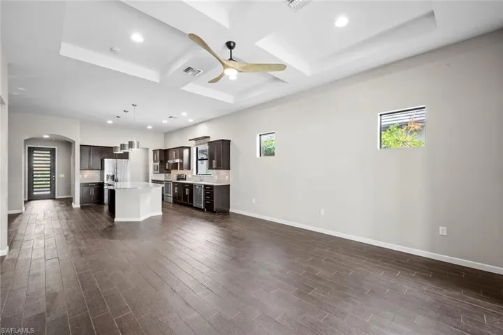 Empty room featuring dark wood finished floors, visible vents, and plenty of natural light