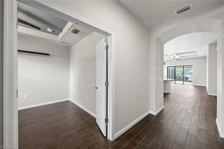 Empty room with dark wood-style floors, a tray ceiling, and visible vents