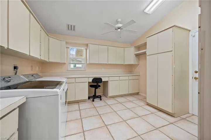 Laundry area with ceiling fan, tile floors, cabinets, and washer and clothes dryer