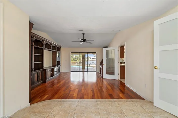 Living room with bookcases, door to dining room on right and lanai straight ahead, wood floors