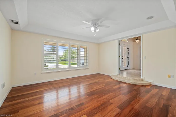 Formal dining with coffered ceiling, wood floor, plantation shutters