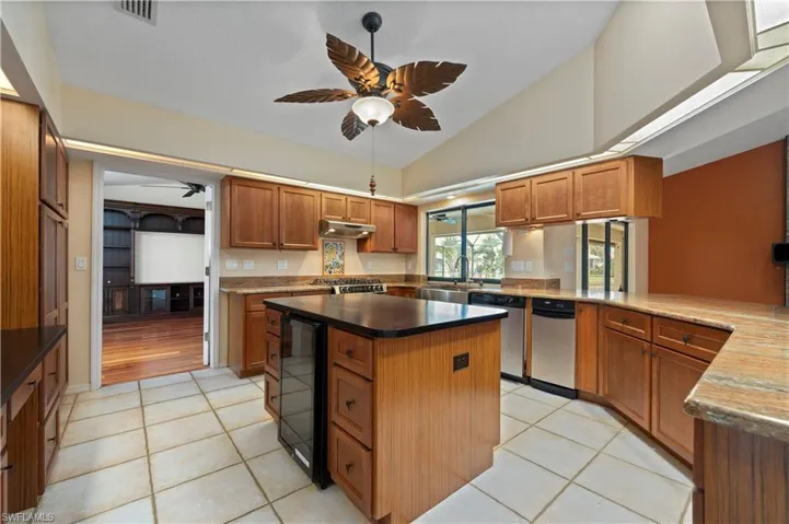 Gas Range, stainless farm sink, view to pool/lanai, pantry closet, beverage cooler, ceiling fan, and a kitchen island