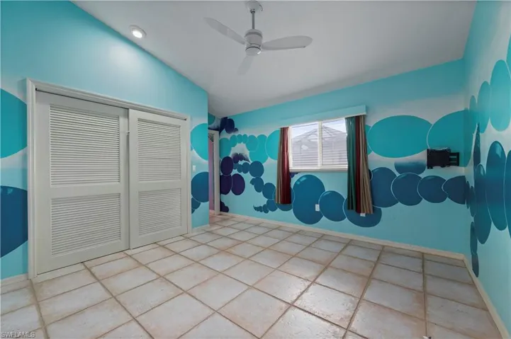 Tiled bedroom with a closet, ceiling fan, and vaulted ceiling