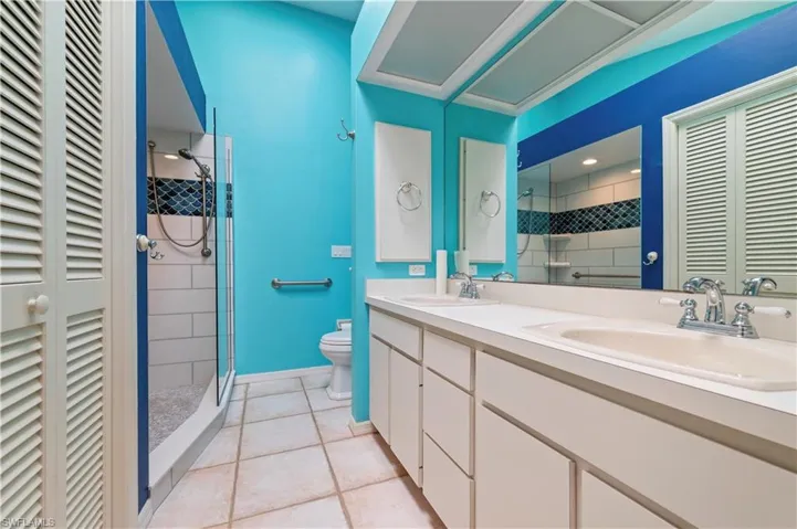 Jack/jill Bathroom featuring vanity, toilet, walk in shower, and tile floors