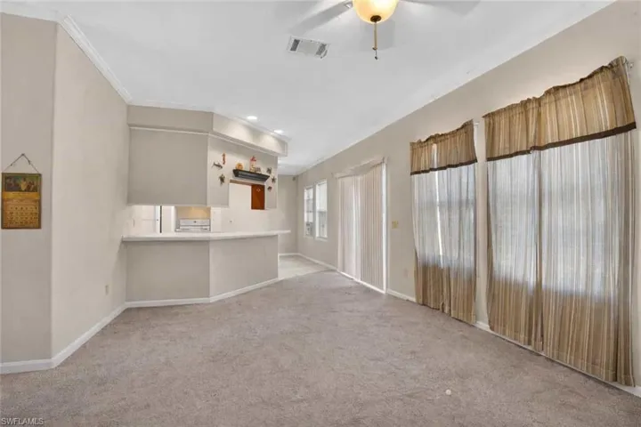 Unfurnished living room with light carpet, ceiling fan, and crown molding