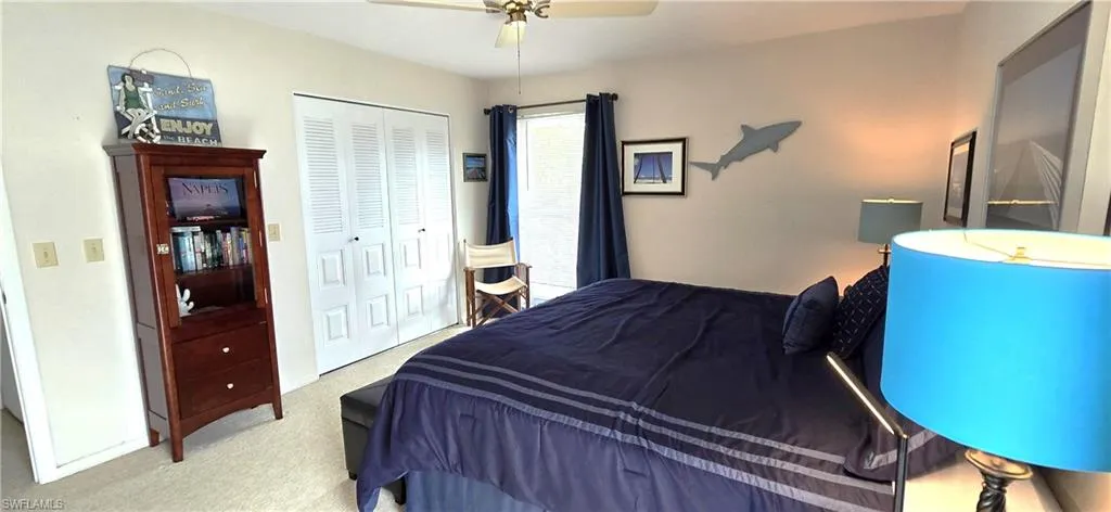 Carpeted bedroom featuring ceiling fan and a closet