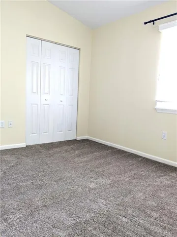 Unfurnished bedroom with baseboards, a closet, and carpet