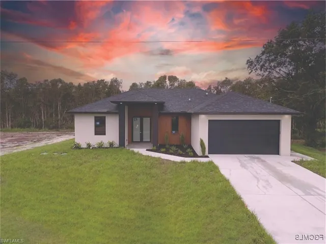 Prairie-style house featuring a yard, an attached garage, driveway, and stucco siding