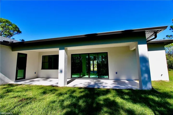 Rear view of property with a yard and a patio