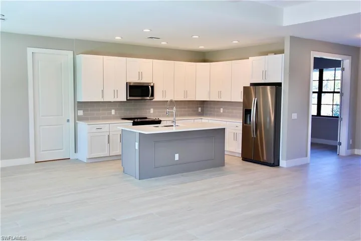 Kitchen with tasteful backsplash, sink, a kitchen island with sink, appliances with stainless steel finishes, and white cabinets