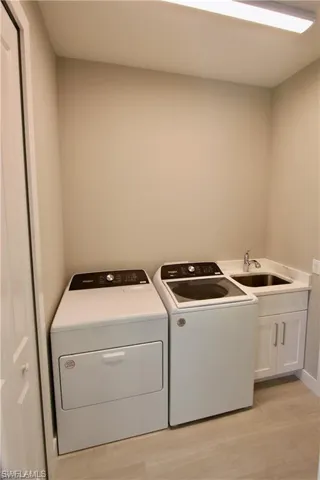 Washroom with cabinets, washer and clothes dryer, and sink