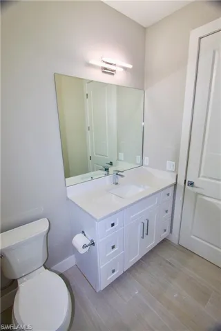 Bathroom featuring toilet, vanity, and wood-type flooring