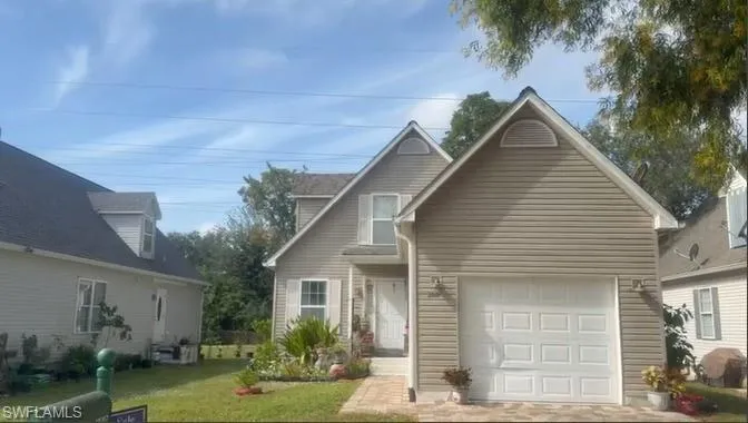Traditional-style house with a front yard and a garage