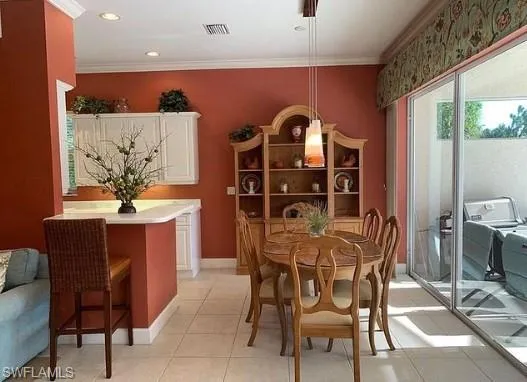 Dining space with light tile patterned floors and crown molding