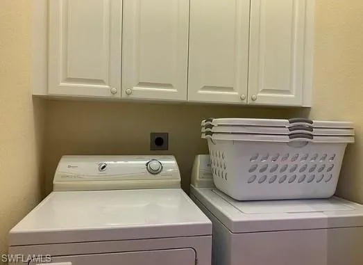 Clothes washing area featuring cabinets and washing machine and clothes dryer