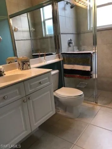 Bathroom with tile patterned flooring, vanity, an enclosed shower, and toilet