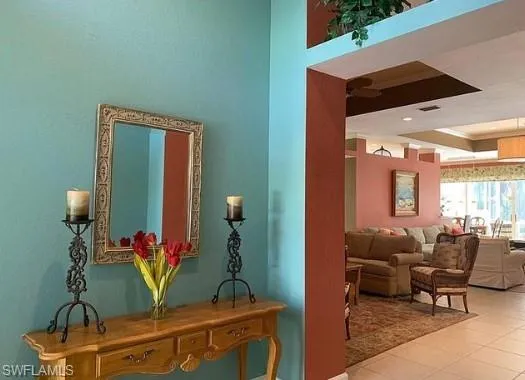 Hallway featuring a tray ceiling and light tile patterned flooring