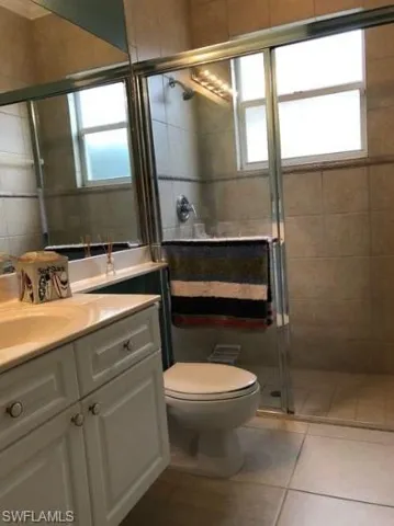 Bathroom featuring tile patterned flooring, vanity, a shower with shower door, and toilet