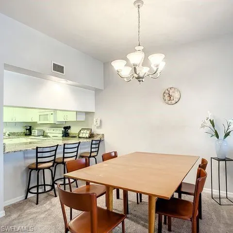 Dining area with a chandelier and light carpet