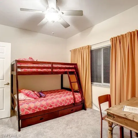 Carpeted bedroom with a ceiling fan