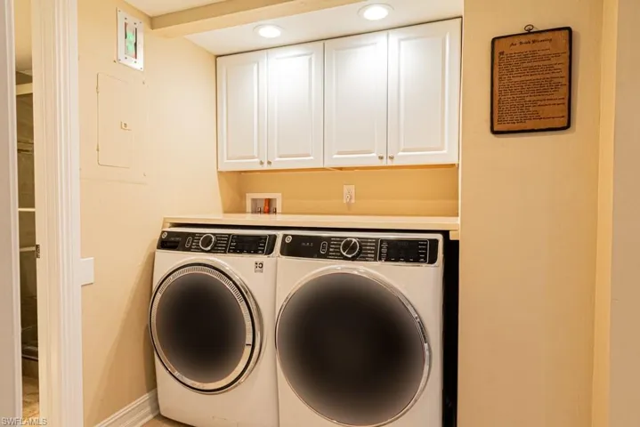 Front loading clothes washer and dryer and featuring cabinets and counter.