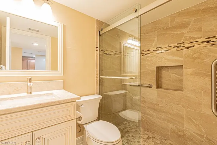 Guest bathroom with large tile shower and toe mold lighting.