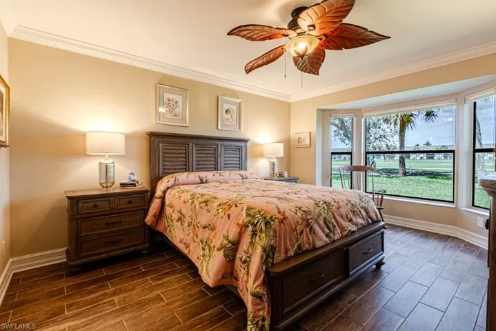 Bedroom with dark hardwood / wood-style flooring, ornamental molding, and ceiling fan