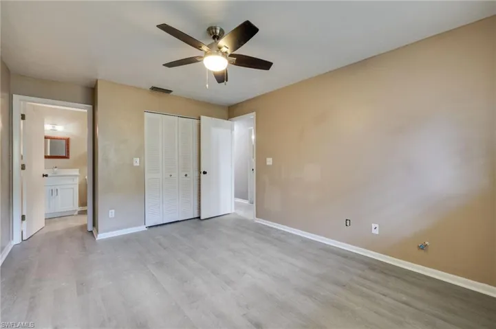 Unfurnished bedroom featuring a closet, a ceiling fan, light wood finished floors, and connected bathroom