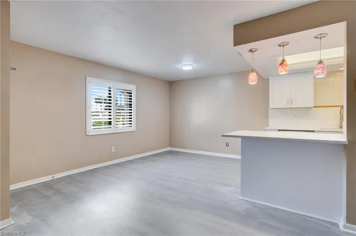 Kitchen featuring white cabinetry, hanging light fixtures, light wood-style flooring, and backsplash
