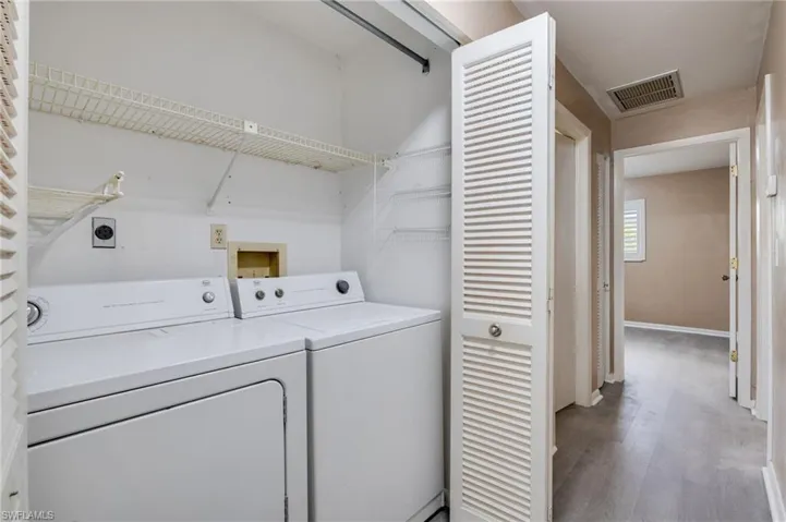 Laundry area with separate washer and dryer and wood finished floors