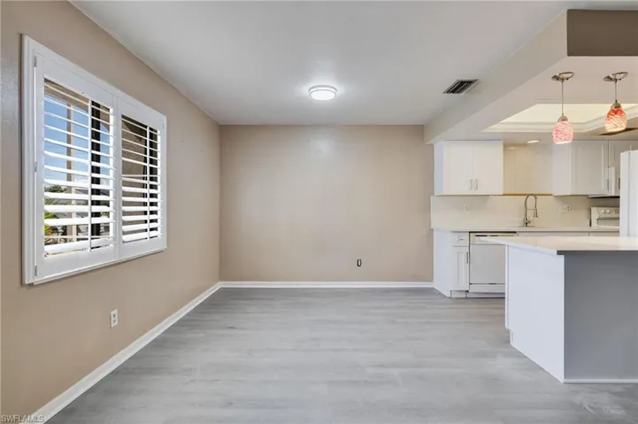 Kitchen featuring white cabinets, pendant lighting, light wood finished floors, tasteful backsplash, and white appliances