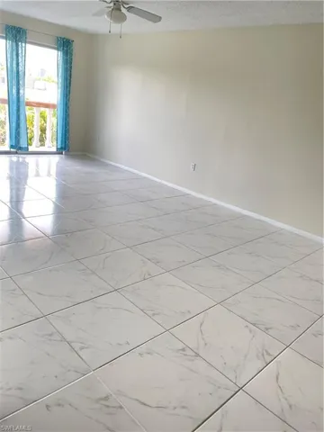 Tiled empty room with a textured ceiling and ceiling fan
